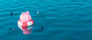 Piggy bank in lifebuoy on blue sea surrounded by sharks, Savings
