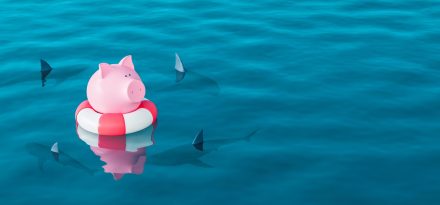 Piggy bank in lifebuoy on blue sea surrounded by sharks, Savings