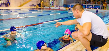 Disabled boy with Down syndrome in swimming cap wearing goggles in swimming pool